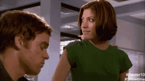 a man and woman are looking at each other in a room . the woman is wearing a green shirt .