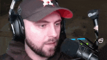 a man with a beard wearing headphones and a hat that has the letter h on it