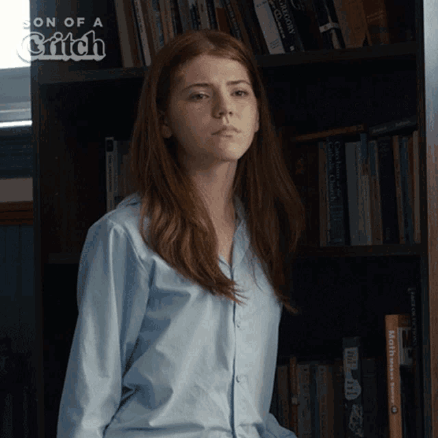 a girl stands in front of a bookshelf with a book titled son of a britch on it
