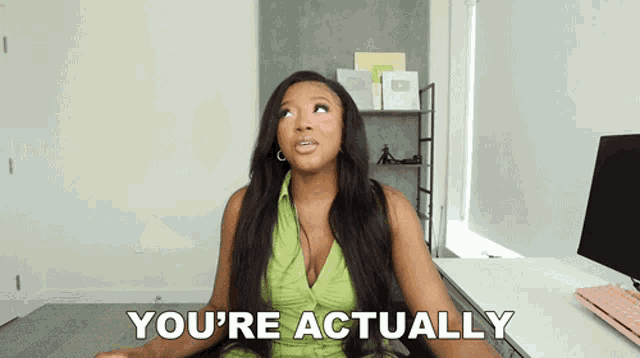 a woman in a green dress says you 're actually in front of a computer