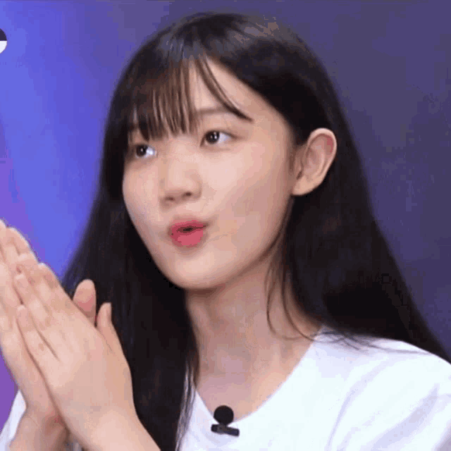 a young girl with long black hair is clapping her hands in front of a microphone