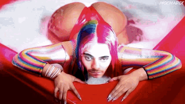a woman with pink hair is laying on her stomach in a bathtub
