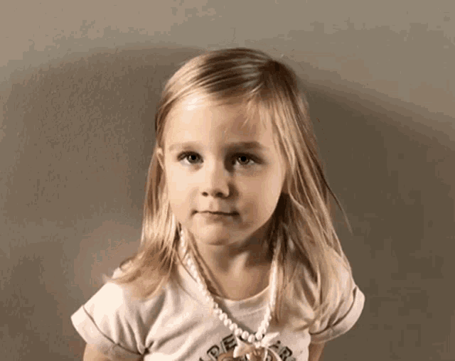 a little girl wearing a pearl necklace and a shirt that says ' abercrombie & fitch ' on it