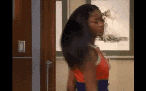 a woman is standing in front of a door in a room with her hair blowing in the wind .