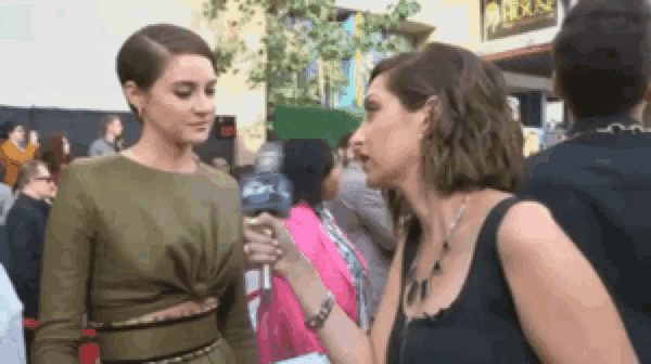 a woman is talking to another woman in a crowd while wearing a green dress .