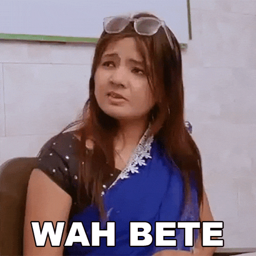 a woman wearing sunglasses and a blue saree is sitting in a chair with wah bete written on her face .
