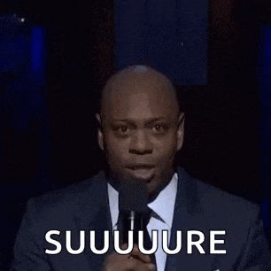 a man in a suit and tie is making a funny face and saying suuuure .