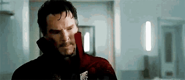 a man in a red coat is standing in a hallway .