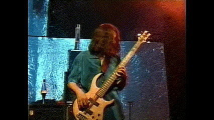 a man with long hair is playing a bass guitar