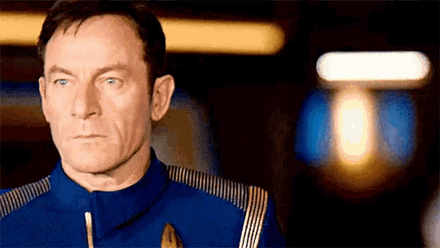 a man in a blue uniform is standing in front of a light .