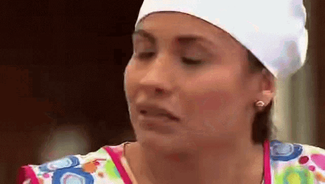 a woman wearing a chef 's hat and a colorful apron is making a face .