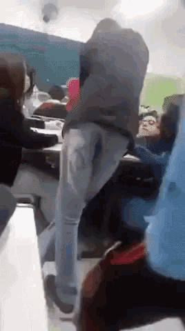 a group of people are standing in a classroom with a man standing in the middle of them