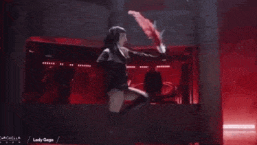 a woman is dancing on a stage while holding a red fan in her hand .