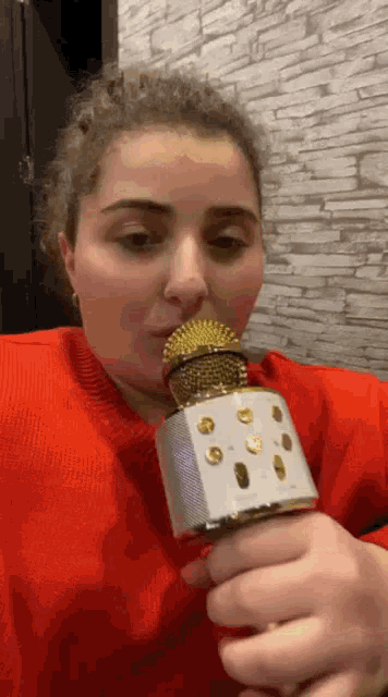 a woman is holding a microphone in her mouth and singing into it .