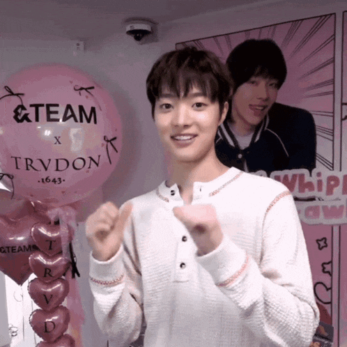 a man stands in front of a pink balloon that says team on it