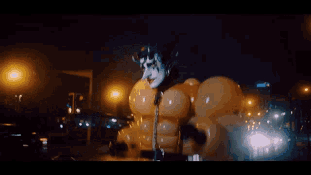 a man in a clown costume is walking down a city street at night .