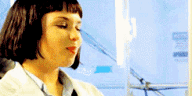a woman in a white coat is sitting in front of a computer screen .
