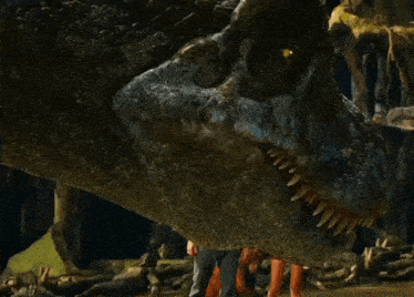 a close up of a dinosaur 's mouth with people standing around