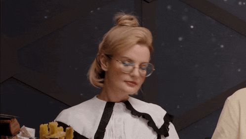 a woman wearing glasses and a white shirt is looking down