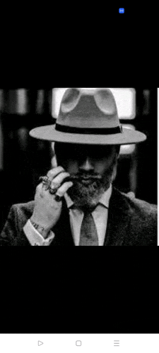a man with a beard wearing a fedora hat and smoking a cigar .