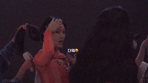 a woman in a yellow top is holding a fan and looking at the camera .