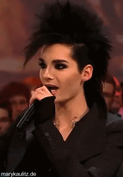 a woman with a mohawk is singing into a microphone while wearing a black jacket .