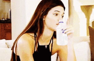 a woman is drinking water from a bottle .
