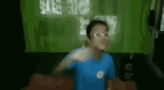 a young boy wearing glasses and a blue shirt is sitting on a couch in a room .