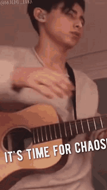 a young man is playing a guitar with the words `` it 's time for chaos '' written below him .