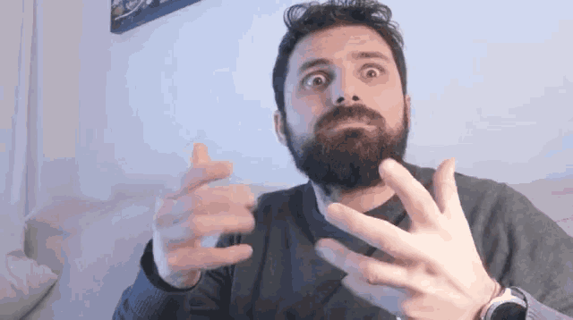 a man with a beard is wearing a watch and making a funny face