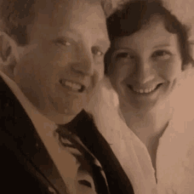 a man and a woman are posing for a picture and smiling for the camera .