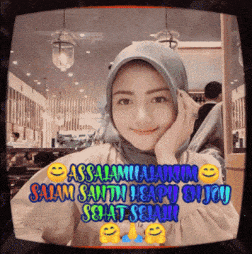 a woman in a hijab is sitting in front of a tv screen that says " assalamualaikum " on it