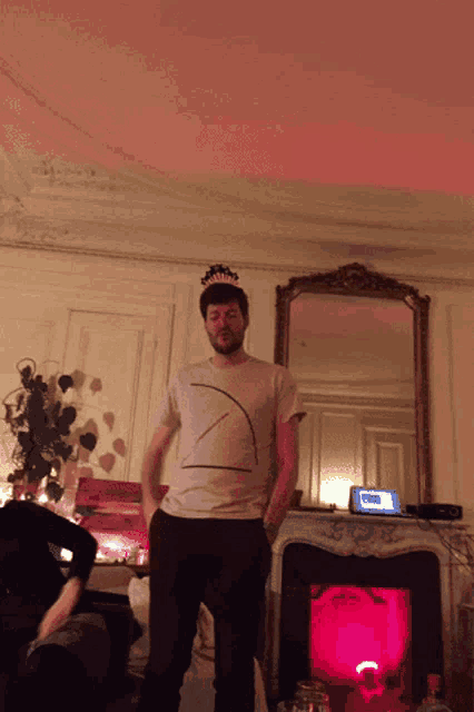 a man wearing a birthday crown stands in a living room