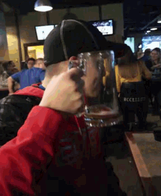 a man in a baseball cap is drinking from a beer glass