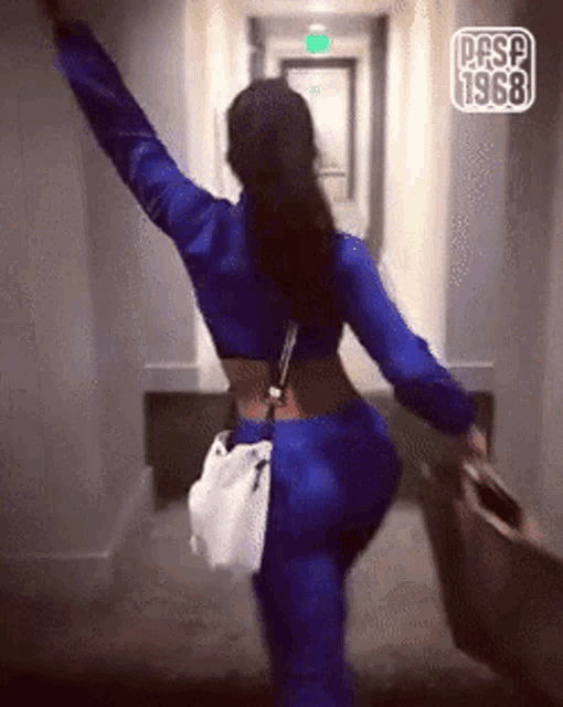 a woman in a blue outfit is walking down a hallway with her arms outstretched and the year 1968 written on the bottom