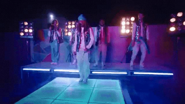 a group of people are dancing on a stage with blue lights .