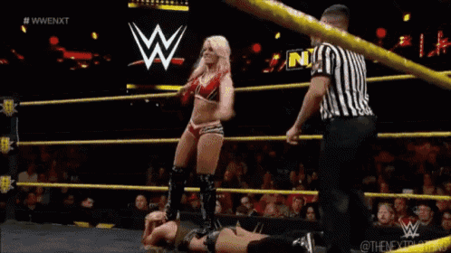 a woman is wrestling in a wrestling ring with a referee watching .