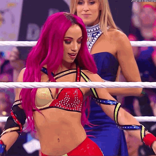 a woman with pink hair is in a wrestling ring with another woman