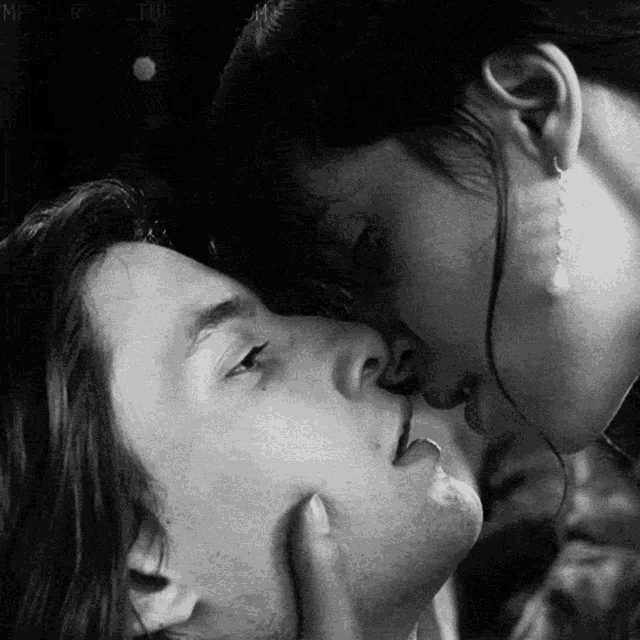 a man and a woman are kissing in a black and white photo .