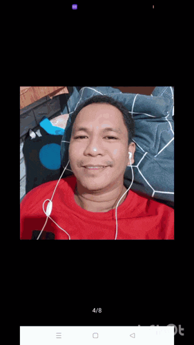 a man in a red shirt is smiling and wearing earbuds