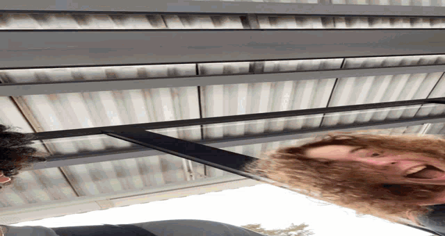 a man with curly hair is upside down and looking down