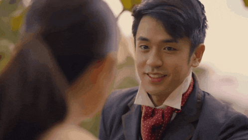 a man in a suit and tie is smiling while looking at a woman