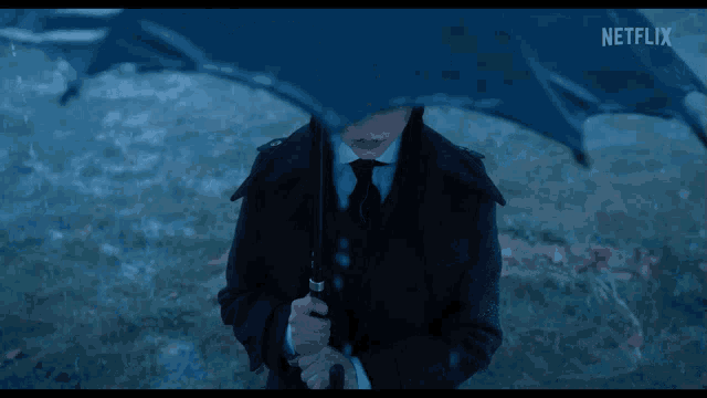 a person in a suit and tie holding an umbrella with a netflix logo behind them