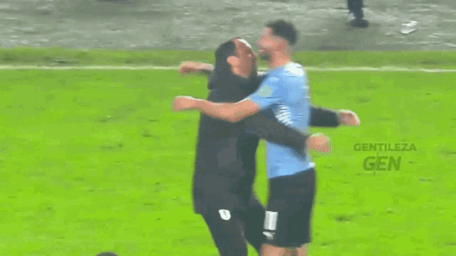 two men are hugging each other on a soccer field . one of the men is wearing a number 11 jersey .