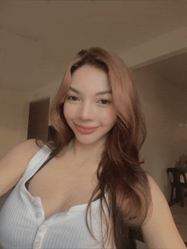 a woman taking a selfie with a white tank top on