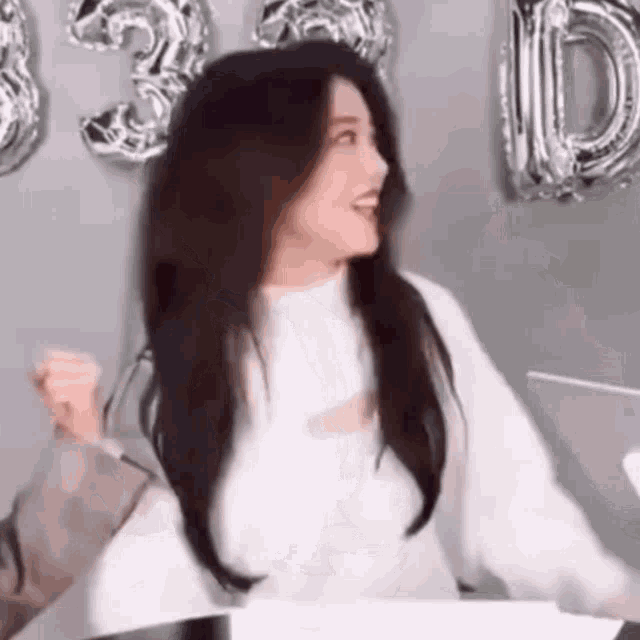 a woman in a white sweater is sitting at a table with her arms outstretched .