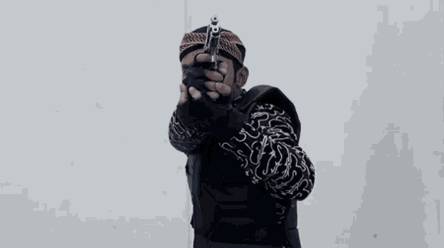 a man is holding a gun in front of his face .