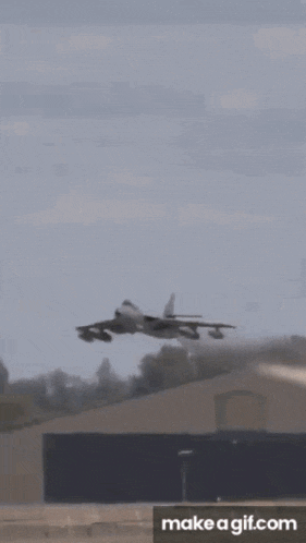 a plane is flying over a field and a make a gif.com button is below it