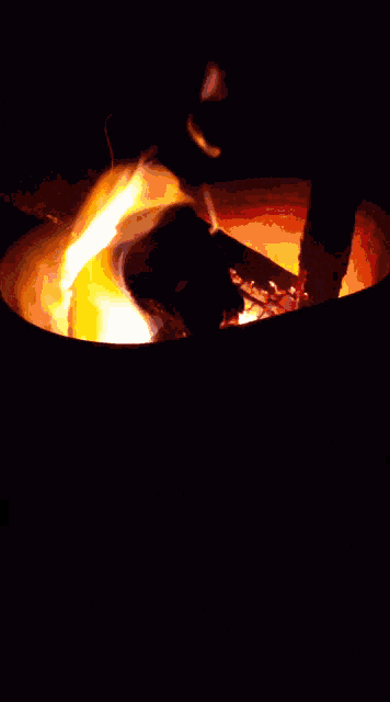 a fire is burning in a metal container with a dark background