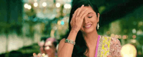 a woman is laughing and covering her face with her hand .